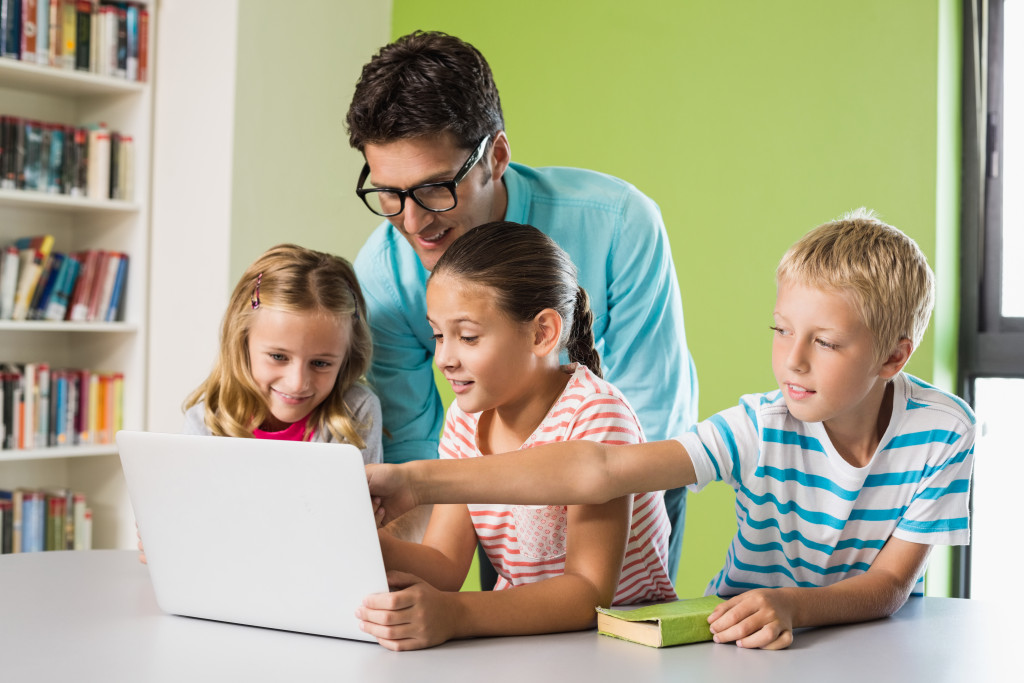 father homeschooling his children with the help of technology